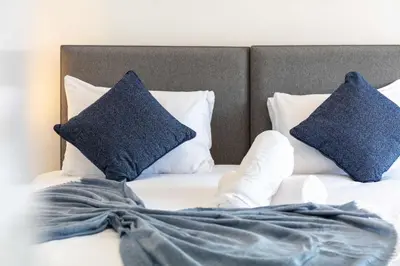 a bed with two blue pillows on top of it at No20 Mansfield - Donnini Apartments in Prestwick
