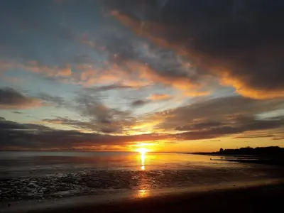 a sunset on a beach with the sun in the sky at Shoreside in Powfoot