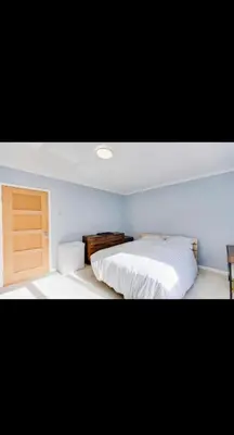 a bedroom with a white bed and a wooden door at Modern home Close to all Cardiff venues in Moffat