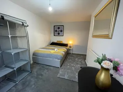 a bedroom with a bed and a vase with flowers at Vibrant Room in Centeral Ayr in Ayr