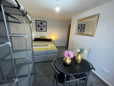 a bedroom with a bed and a table with flowers on it at Vibrant Room in Centeral Ayr in Ayr