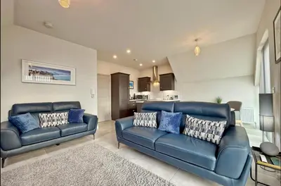 a living room with two blue couches and a kitchen at Stylish apartment in Portstewart in Moffat