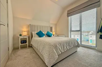 a bedroom with a bed with blue pillows and a window at Stylish apartment in Portstewart in Moffat