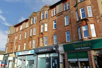 a large brick building on a city street with stores at 2 bedroom first floor flat- Bonnie Stays in Troon