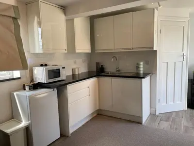 a kitchen with white cabinets and a microwave at Detached Annexe in Moffat