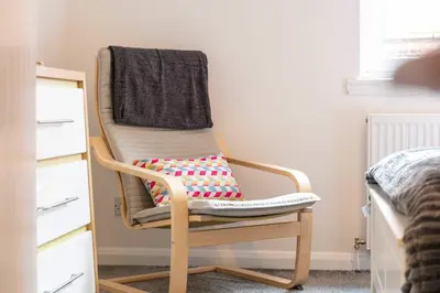 a rocking chair with a blanket on it in a bedroom at Albyn Retreat - Donnini Apartments in Prestwick