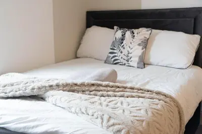 a white bed with a blanket and pillows on it at Saint Nico in Carlisle