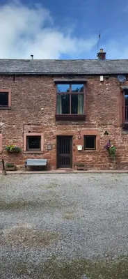 a brick building with windows and a bench in front at Ash Lodge at The Barn in Gosforth
