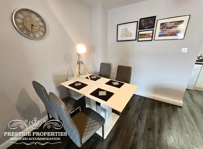 a dining room table with chairs and a clock on the wall at 12 Seacote Garden by Prestige Properties SA in St Bees