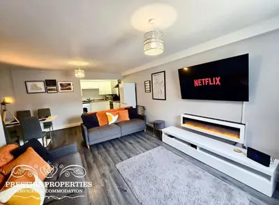 a living room with a couch and a tv on a wall at 12 Seacote Garden by Prestige Properties SA in St Bees