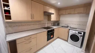 a kitchen with wooden cabinets and a washer and dryer at comfy residence in Moffat