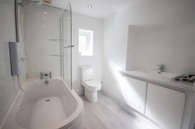a bathroom with a tub and a toilet and a sink at Modern 2Bed Garden Apartment in Heart of Penarth in Moffat