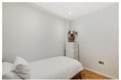 a white bedroom with a bed and a vase with flowers at 2 Bedroom Apartment Queensway in Moffat