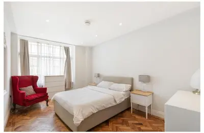 a bedroom with a bed and a red chair at 2 Bedroom Apartment Queensway in Moffat