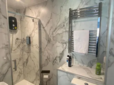 a bathroom with a shower and a marble wall at Serenity Suites in Douglas
