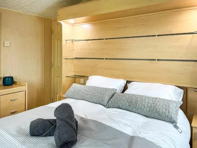 a bedroom with a large white bed with a wooden headboard at Keswick Reach in Cockermouth