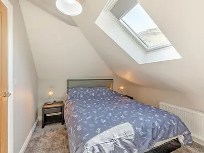 a bedroom with a bed and a skylight at Tower Cottage in Glenridding