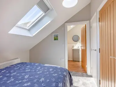a bedroom with a blue bed and a skylight at Tower Cottage in Glenridding