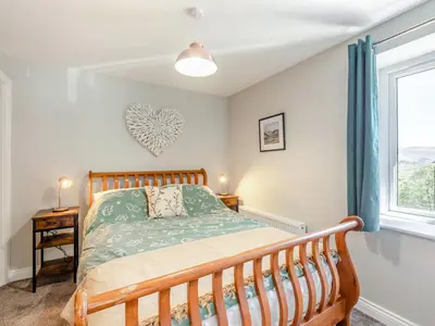 a bedroom with a wooden bed and a window at Tower Cottage in Glenridding