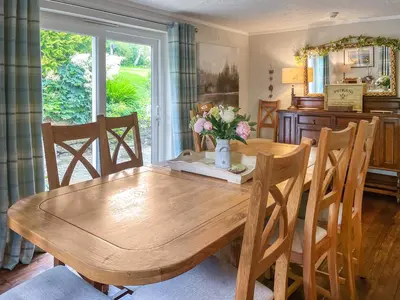a dining room table with a vase of flowers on it at Gillhead Farm Cottage in Troutbeck