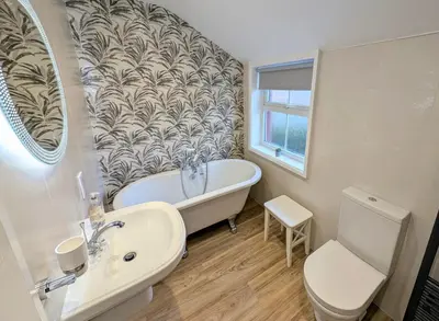 a bathroom with a tub and a toilet and a sink at Two Chimneys in Keswick