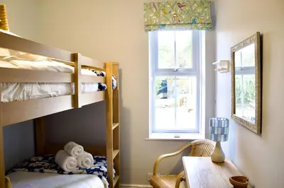 a bedroom with bunk beds and a desk and a window at Two Chimneys in Keswick