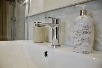 a bathroom sink with a bottle of hand soap on it at Two Chimneys in Keswick