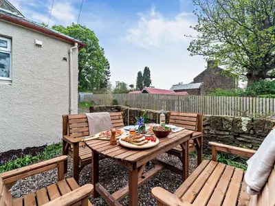 a wooden table and chairs on a patio at 2 Bed in Maybole 96012 in Maybole