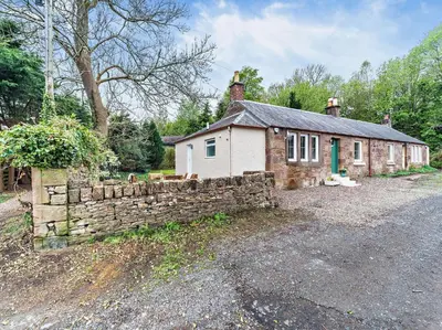 a brick house with a stone wall next to a building at 2 Bed in Maybole 96012 in Maybole