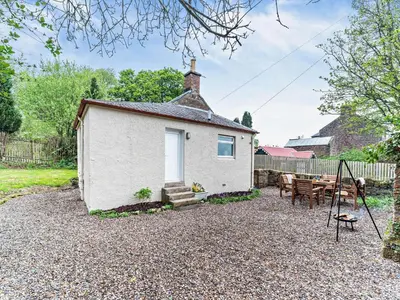 a small white cottage with a table and chairs at 2 Bed in Maybole 96012 in Maybole
