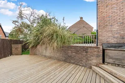 a patio with a brick wall and a wooden deck at 5 Bed in St. Bees oc-w32446 in St Bees