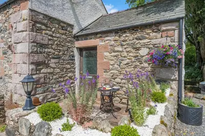 a stone cottage with a table and flowers at 1 Bed in Troutbeck oc-l32563 in Troutbeck
