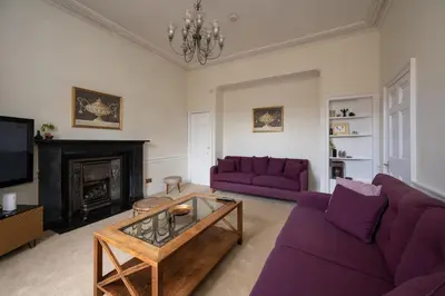 a living room with purple couches and a fireplace at Elegant Town house in Edinburgh in Moffat