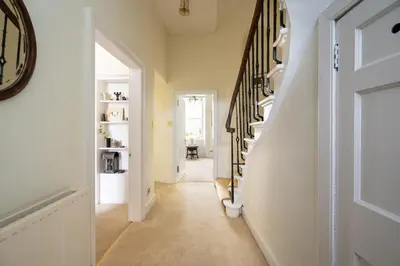 a hallway with white walls and stairs with a clock at Elegant Town house in Edinburgh in Moffat