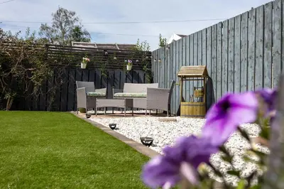 a garden with chairs and a table and a fence at No15 Ellis House - Donnini Apartments in Kilmarnock