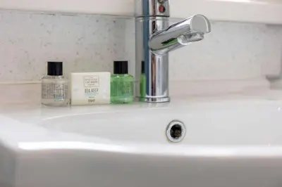 a bathroom sink with two bottles of soap and a faucet at No15 Ellis House - Donnini Apartments in Kilmarnock