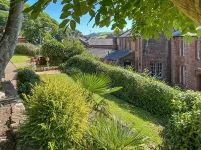 a garden with bushes and a brick building at Abbey Cottage in St Bees