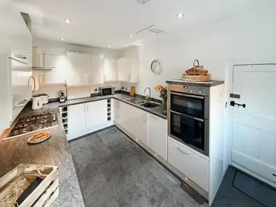 a kitchen with white cabinets and a stove top oven at Abbey Cottage in St Bees
