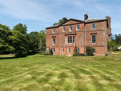 an old brick building on a grass field at Amisfield Tower in Dumfries