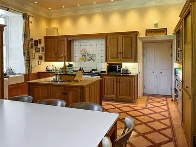 a kitchen with wooden cabinets and a white counter top at Amisfield Tower in Dumfries