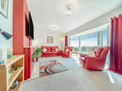 a living room with two red chairs and a tv at Hydee House in Dumfries