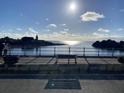 a bench sitting on a sidewalk near the water at Number 26 in Portpatrick