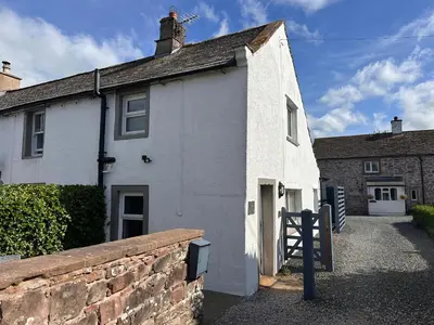 a white house with a brick wall in front of it at Charming cosy cottage near the Lake District in Penrith
