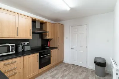 a kitchen with wooden cabinets and a white door at Lovely 2 Bed Harbourside Apartment with Sea Views in Whitehaven