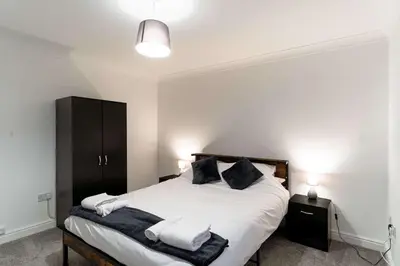 a bedroom with a bed with white sheets and black pillows at Lovely 2 Bed Harbourside Apartment with Sea Views in Whitehaven