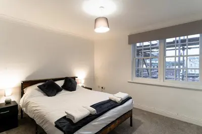 a bedroom with a bed with black pillows and a window at Lovely 2 Bed Harbourside Apartment with Sea Views in Whitehaven