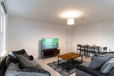 a living room with a couch and a tv and a table at Lovely 2 Bed Harbourside Apartment with Sea Views in Whitehaven