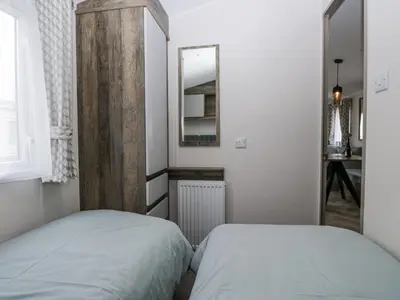 two beds in a small room with a mirror at Puffin in St Bees