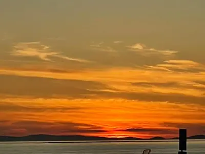 a sunset over a body of water with a lighthouse at Sea view Villa Holiday and Corporate Let Accommodation in Prestwick