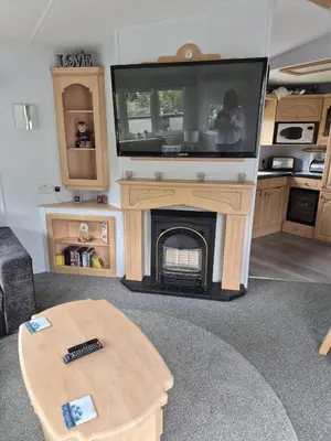 a living room with a fireplace with a tv on top at Shep2 Caravans in Ballantrae